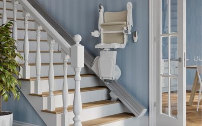 LSM Mobility Un monte-escalier droit beige installé sur un escalier en bois clair avec des balustres blancs, contre un mur bleu clair. Une solution d'accessibilité élégante pour la maison.